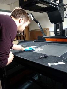 A trainee arranges a record on a table to be photographed from above