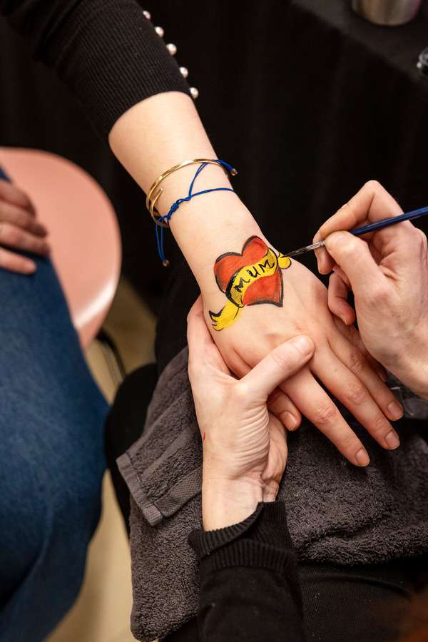 A hand with a heart with the text 'Mum' being painted onto it.