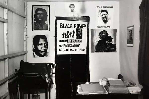 A small, cramped room with a desk covered in files and lots of civil rights posters on the wall.