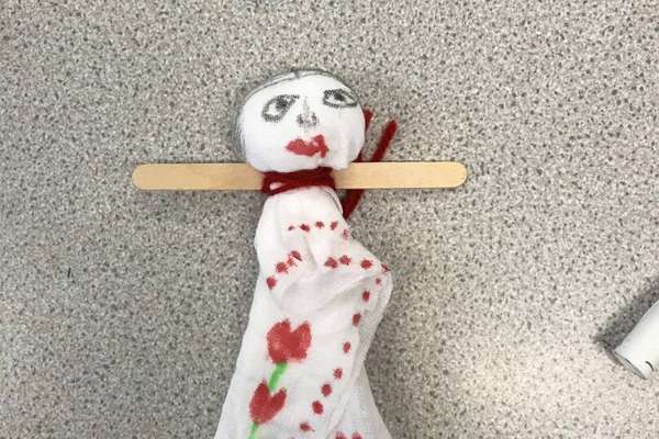 A doll made of a piece of cloth and lolly stick.