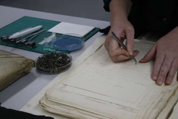 Hands carefully remove nails sticking out of paper