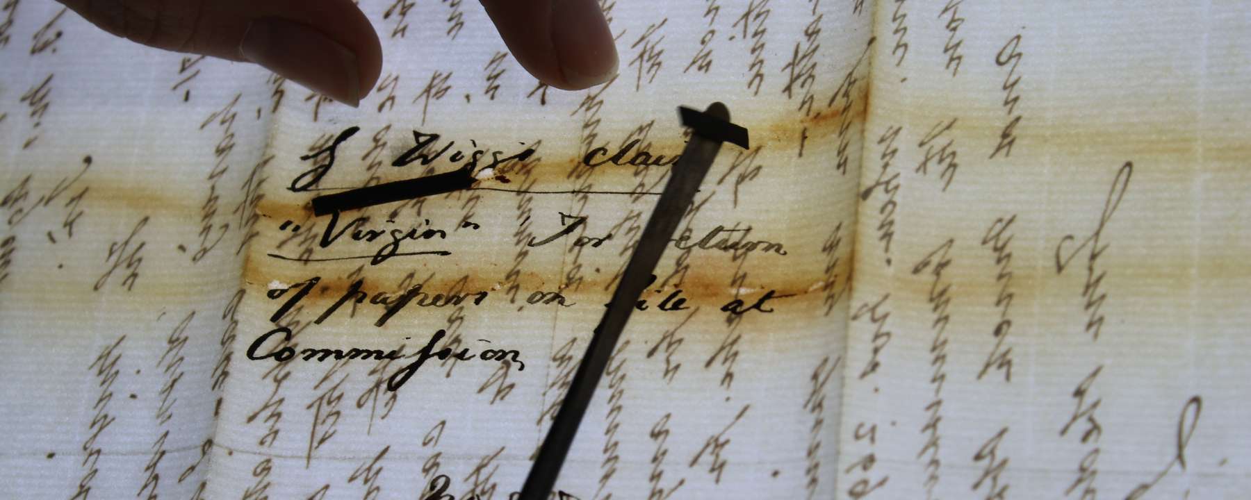 A small metal instrument removes a degraded rubber band that was stuck to a paper letter.