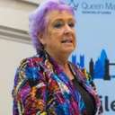 Gill is shown speaking at an event.