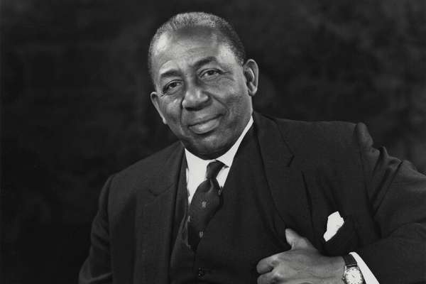 Sir Learie Constantine, a middle aged, smartly dressed Black man. He looks directly into the camera