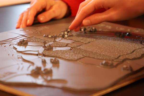 Children's hands touch a tactile model of a medieval map.