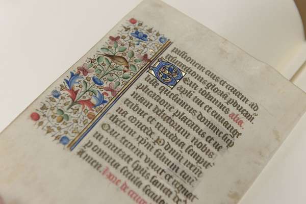 Close-up of a single page document. The page contains ornate latin script, an illuminated border and an illuminated capital letter, typical of the medieval era.