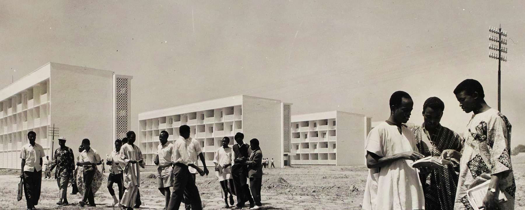 A black and white photo of people standing in front of buildings