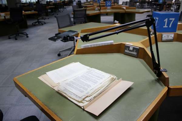 A phone is placed into a camera stand over a document resting on a table
