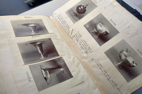 A book is open to a A3 page with six black and white images of metal dishes