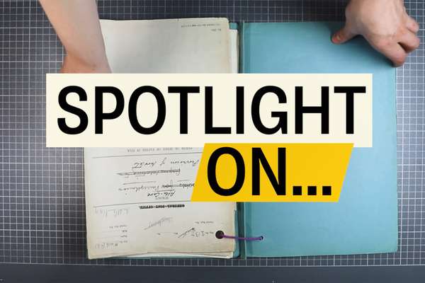 Screenshot of a video. Large letters reading 'Spotlight On' fill the screen. Behind them hands hold a historic document.