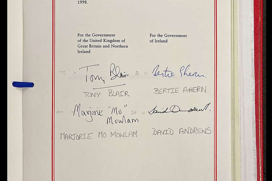 A formal document in a red folder. The page is signed by four politicians.
