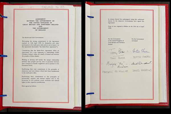 Two pages of a document in a red binder. At the bottom of one page it is signed by four politicians.