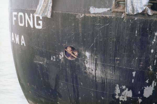 Two young refugees look out of small rounded window aboard the Huey Fong.