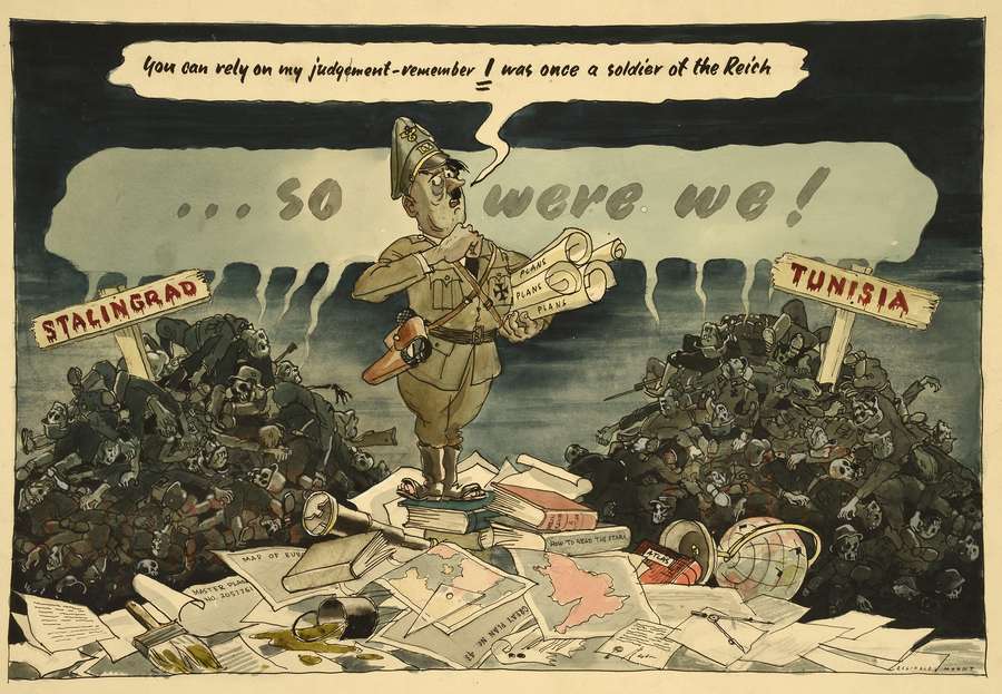 Hitler wearing a uniform and military cross. He has a belt with a gun. He is standing on a pile of plans between two heaps of dead soldiers with skulls- one pile labelled ‘Stalingrad’ and the other ‘Tunisia’. He is holding four rolled-up plans.