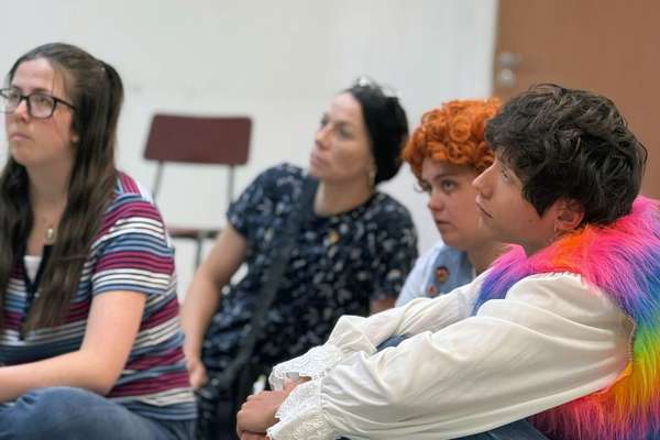 Four actors sitting down on the floor during rehearsals.