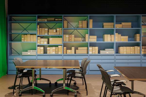 A room with shelves on the back wall full of archival boxes. In front are tables and chairs set up for a school group.