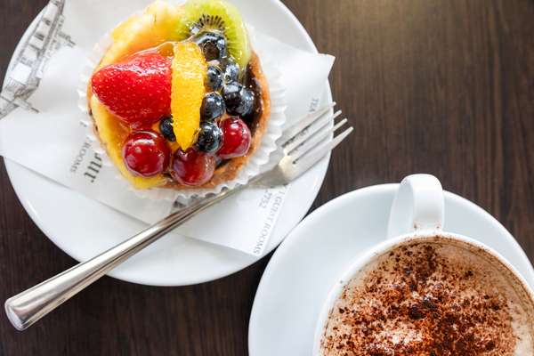 Close up view of a fruit tart and a cappuccino.