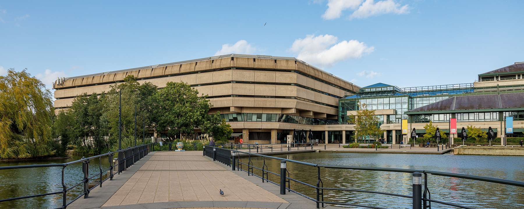 A path between two man-made lakes leads to The National Archives building, a brutalist concrete structure on one side and a glass construction on the other.