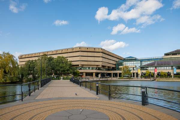 A path between two man-made lakes leads to The National Archives building, a brutalist concrete structure on one side and a glass construction on the other.