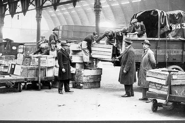Photograph of a group of workers in hats loading boxes on to a truck.