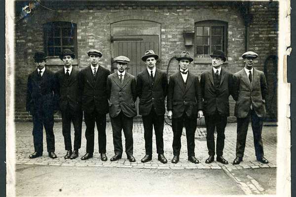 Photograph of eight men standing in a line.