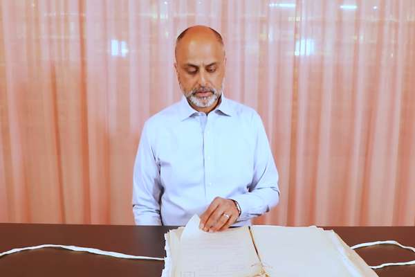 Iqbal Singh looks down at a large, open folder of documents, about to turn a page.