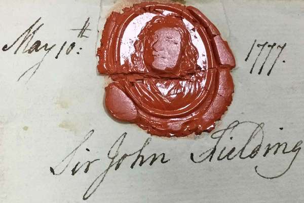 A red wax seal showing the outline of a man's face, with hair dropping past his shoulders..