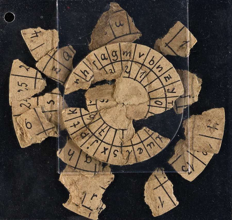 A paper code wheel ripped into many pieces.