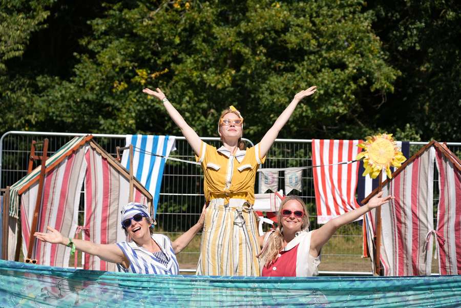 Three people celebrating in front of deck chairs and a swimming pool