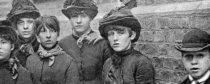 A group of young working class women stand together looking directly at the camera