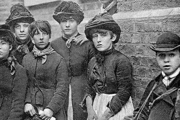 A group of young working class women stand together looking directly at the camera