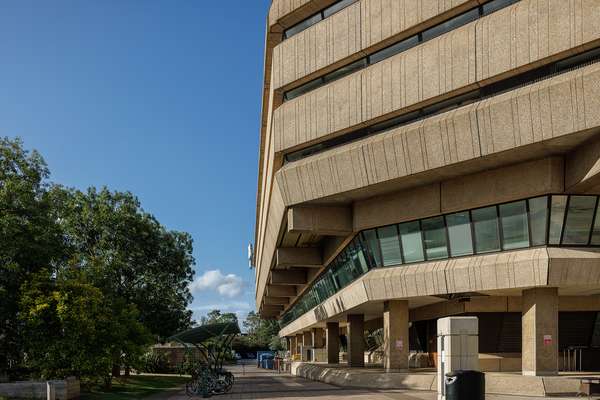 The concrete face of the National Archives' building next to trees and a clear blue sky.