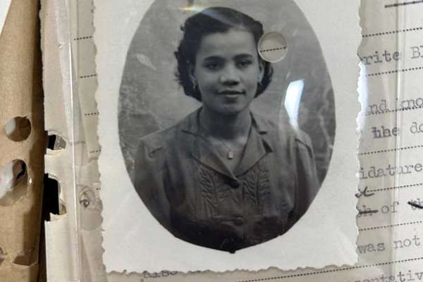 Black and white portrait photograph of a smartly-dressed young woman with a modest smile.