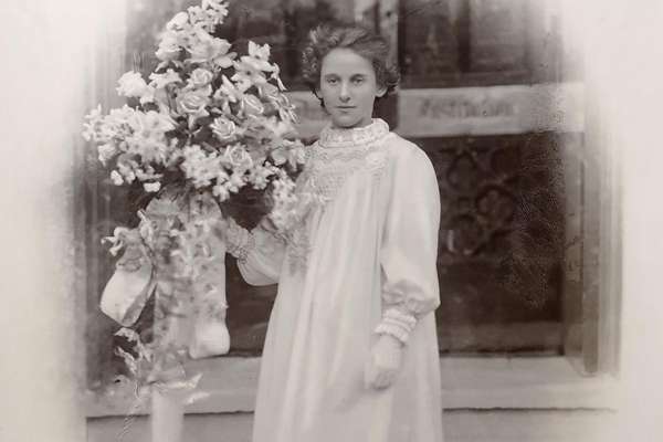 Sepia photograph of a young woman with a faint smile holding a bouquet of flowers.