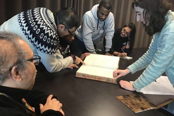 A group of people looking at a book on a table.