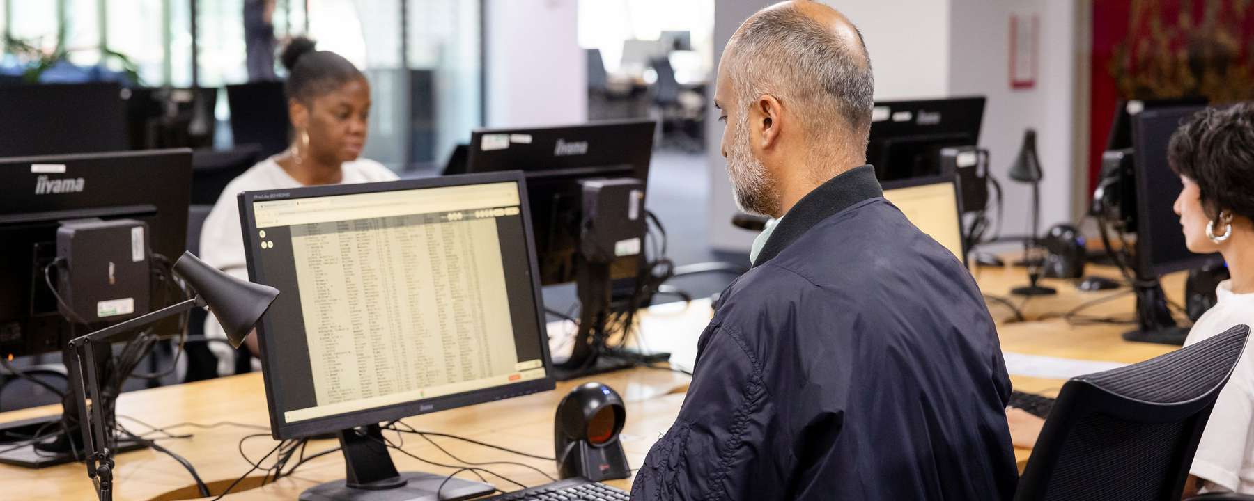A person sits doing research at a bank of computers.