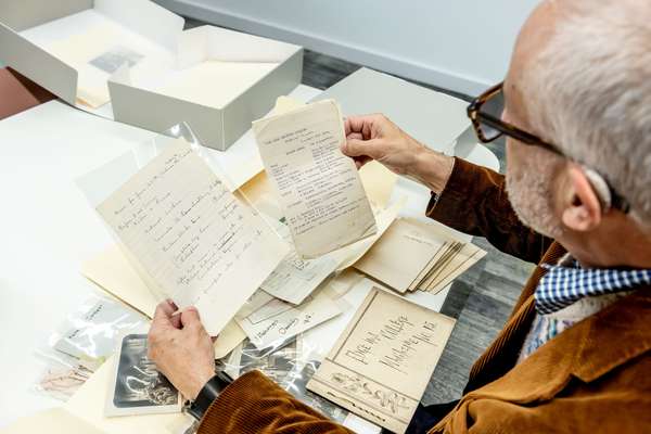 A person holds archival documents and looks at them.