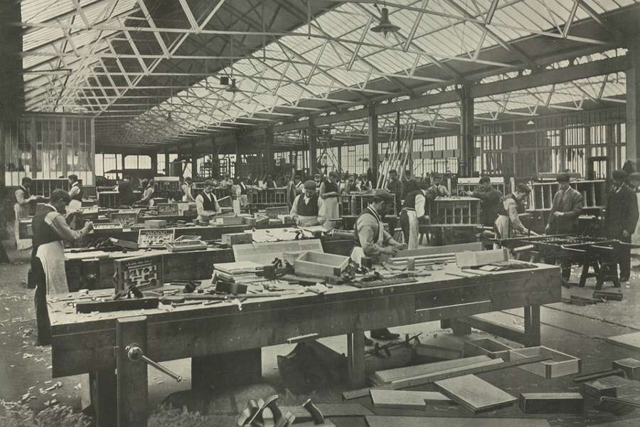 Photograph of workers in a massive sawmill working on heavy machinery.