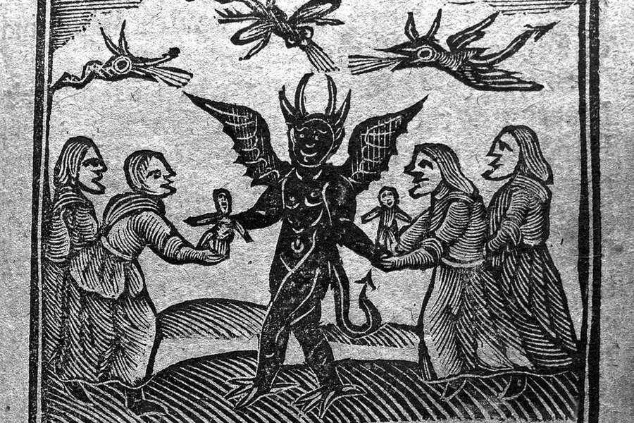 A black and white etching of a devil, a group of witches, and dragons flying in the sky.