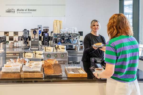 The National Archives coffee bar. A visitor is handed a slice of pie. A coffee machine is visible along with lots of cakes and pastries.