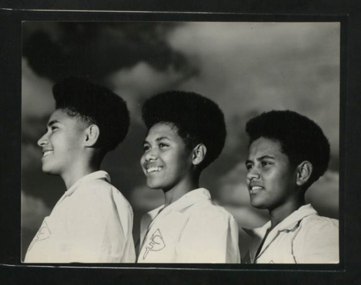 Three young people with afros smiling and looking to the side of the camera.