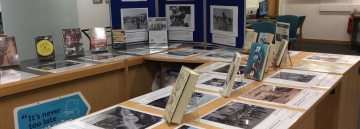 An exhibition in a library consisting of archival photographs, displayed books, and explanatory texts.