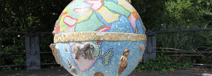 A sculpture consisting of a ceramic globe with a mosaic representing countries, continents, and the equator. Relief sculptures of creatures including an elephant and a mermaid are placed on the globe.