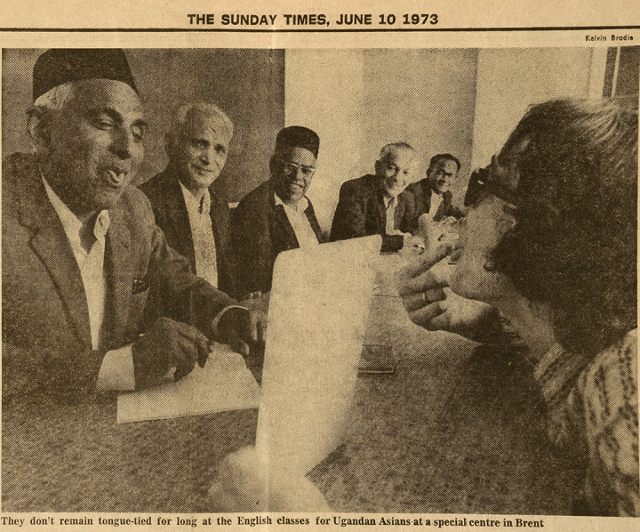 Photograph from a newspaper article showing an older man jokingly trying to curl his tongue in front of a younger man who is pointing at his tongue. A caption reads 'They don't remain tongue-tied for long at the English classes for Ugandan Asians at a special centre in Brent.'