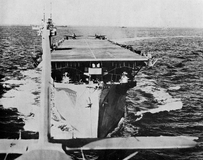 A shot of HMS Biter, a convoy escort carrier, at sea, taken from the back of an aeroplane which has apparently just taken off from the carrier, in 1944 (catalogue reference ADM 199/2061).