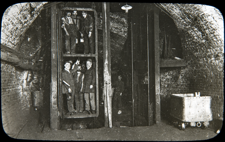 Miners squeezed into an underground lift in an underground chamber. This image is from a collection of photographs, inherited by the National Coal Board, taken by Reverend FW Cobb, Rector of Eastwood, Nottinghamshire between 1907 and 1914 (catalogue reference COAL 13/24).