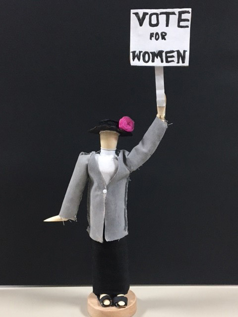 Small sculpture of a suffragette holding a sign saying 'Vote for women'.