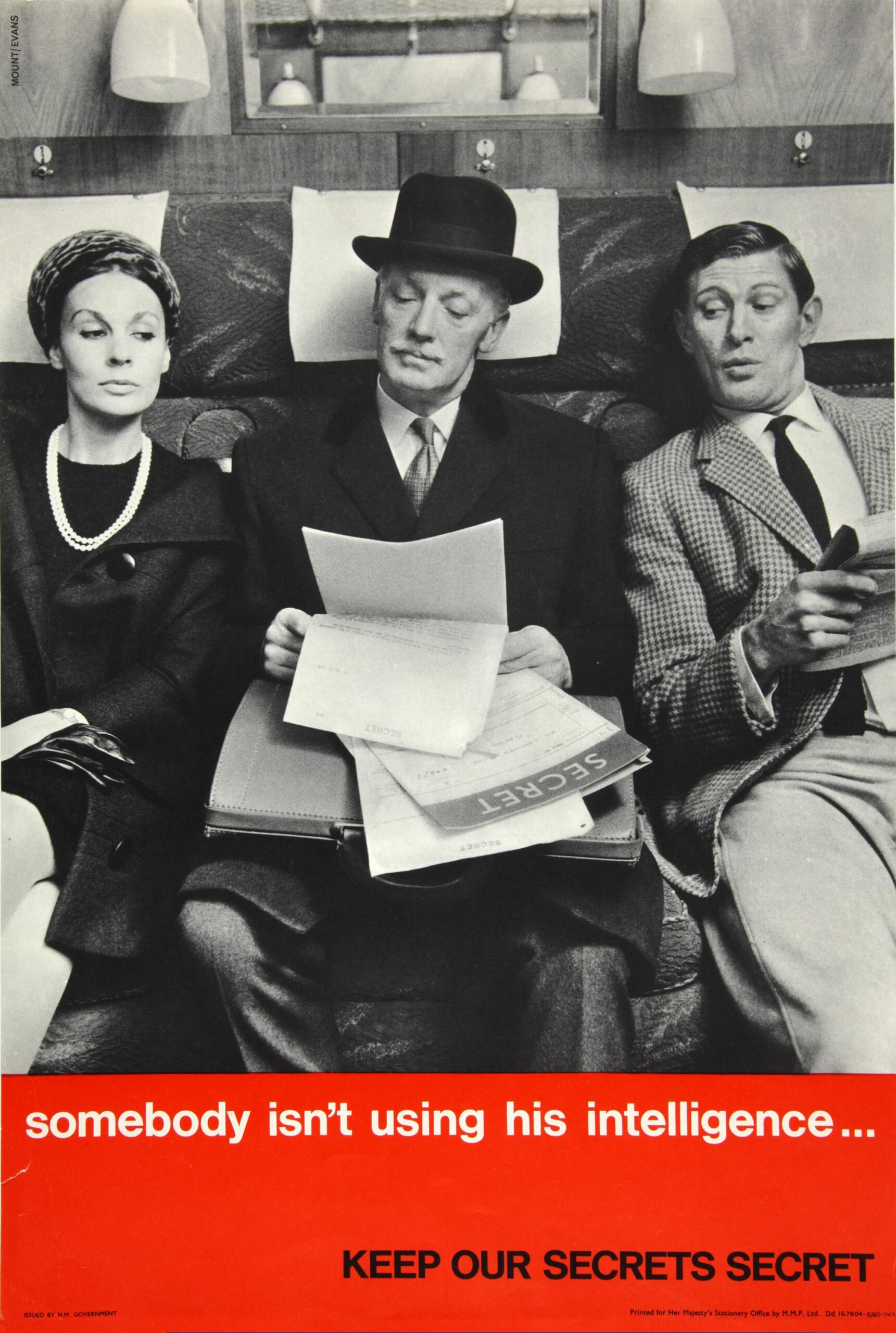 A man in a bowler hat reads papers marked Secret as a man and a woman read over his shoulder.