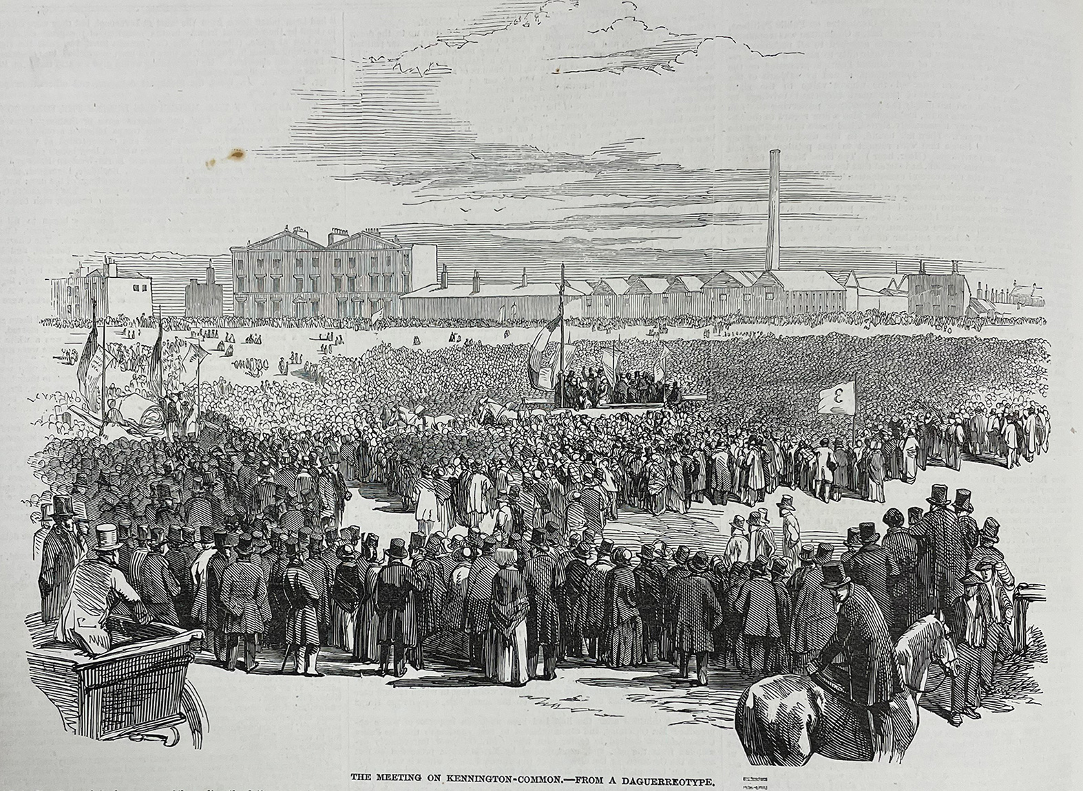 Image caption reads: The meeting on Kennington Common-from a Daguerreotype’. Crowd of people with men in top hats in large open ground with building with large chimney in background. Platform with flags and people standing in centre. Man on horse in foreground.