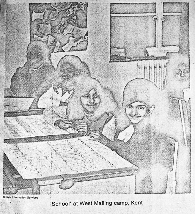 Photograph of children at school desks smiling at a camera. School, at West Malling Camp, Kent